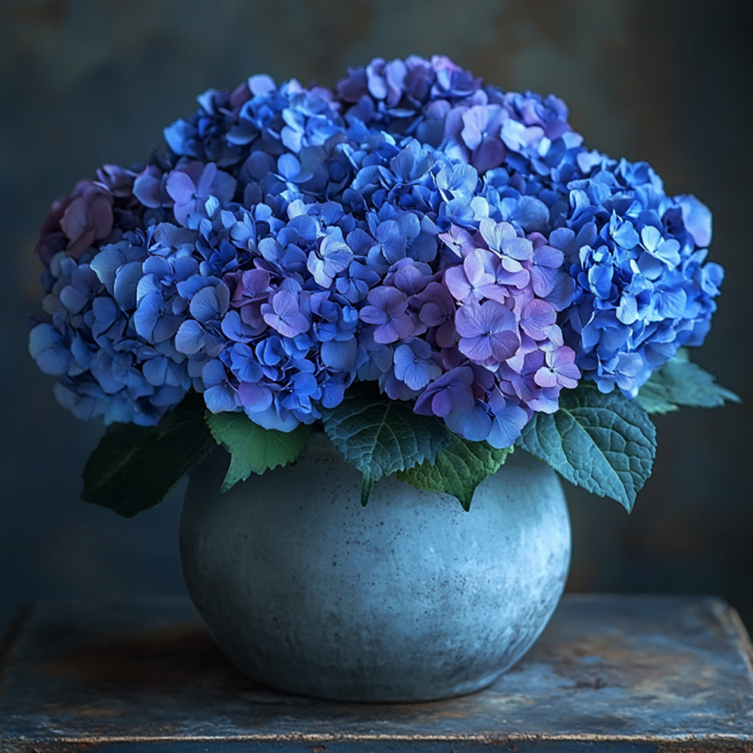 Elegant arrangement of deep blue and lavender hydrangeas in a rustic stone vase — a striking floral design by Flowers Lounge by Iness, ideal for luxury gifts, timeless home decor, and elevated event styling