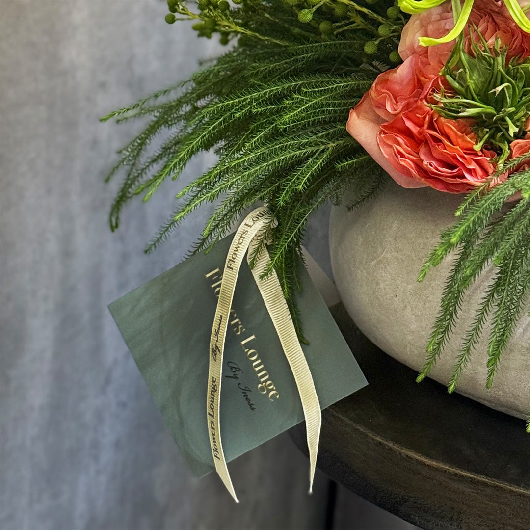 Detailed view of a floral arrangement in a modern cement vase with a branded ‘Flowers Lounge by Iness’ tag and ivory ribbon — handcrafted and available for delivery across Calabasas, El Segundo, West Covina, and Santa Monica