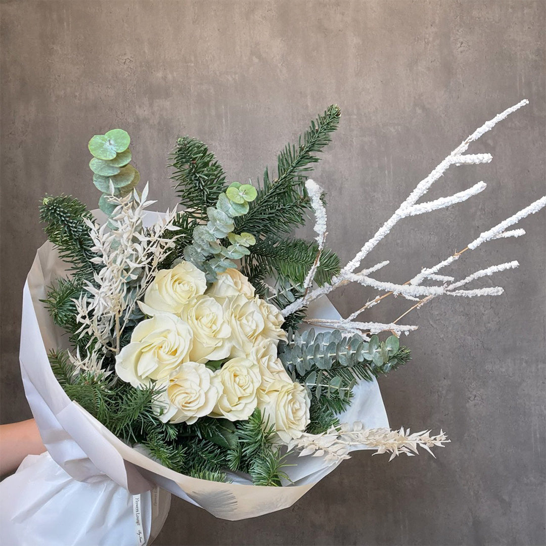 White roses, pine branches, and frosted stems in winter bouquet – Snowfall Elegance by Flowers Lounge