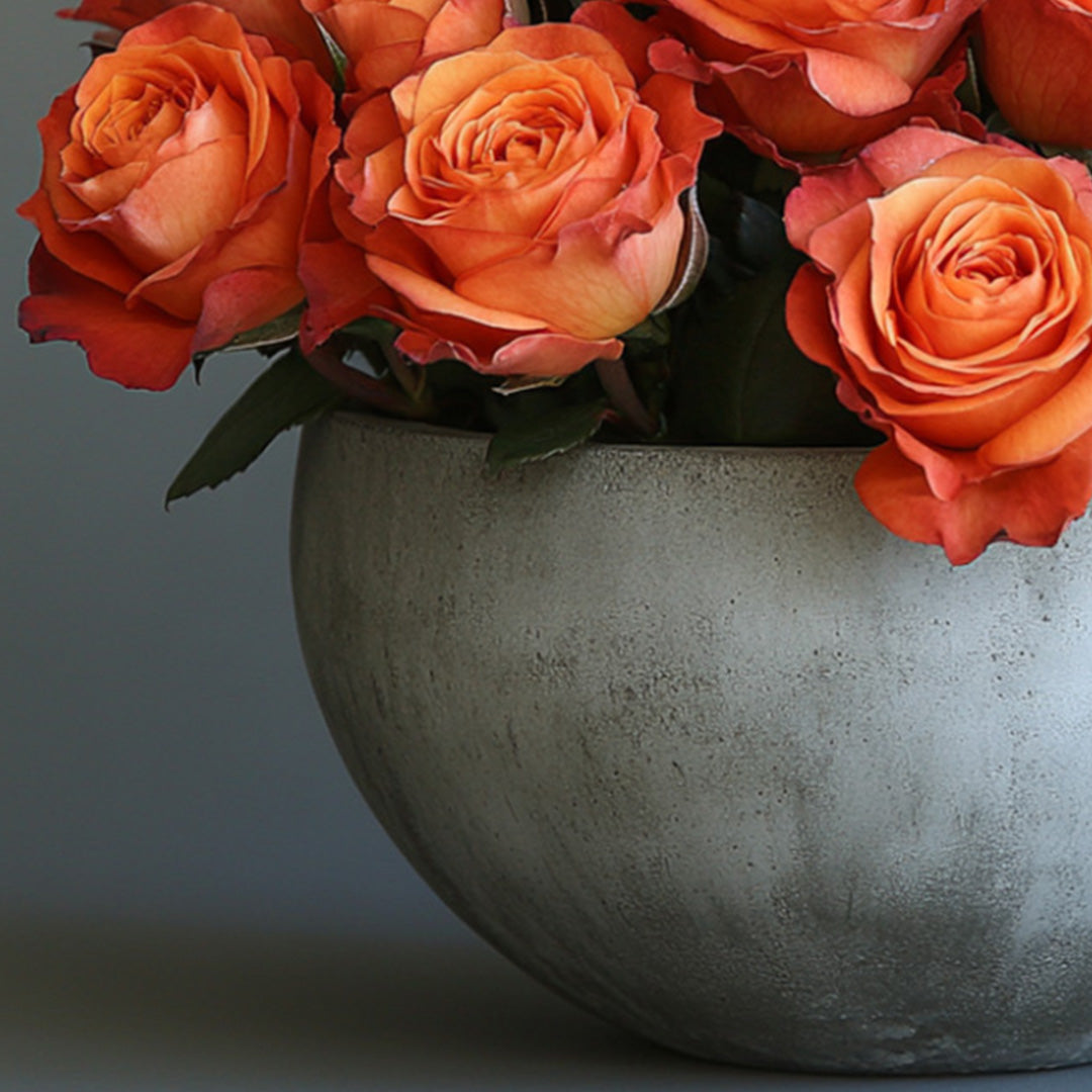 Close-up of vibrant orange roses in a sleek gray vase, showcasing a fresh and elegant floral arrangement.