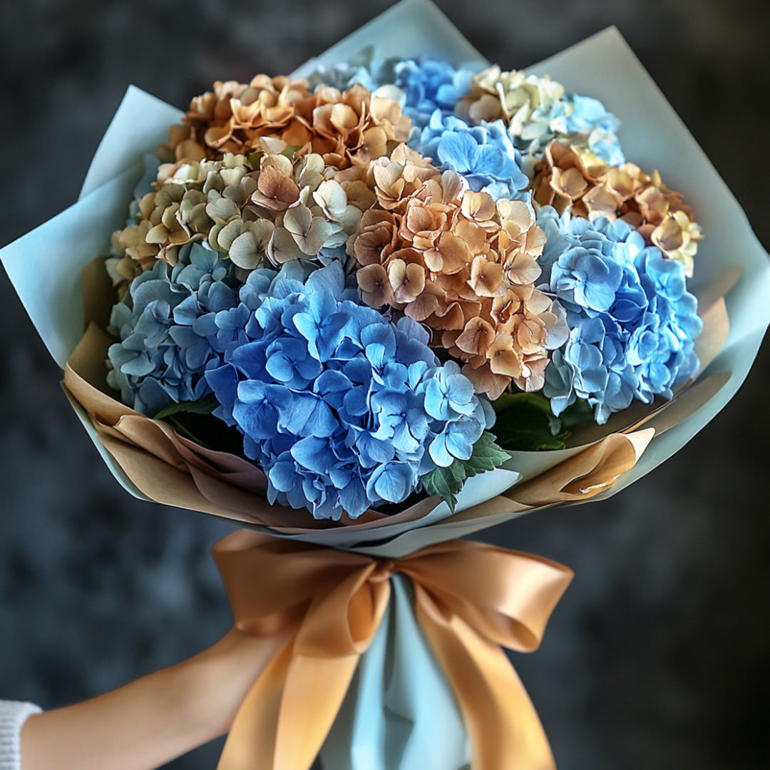 Elegant hydrangea bouquet with shades of blue and golden blossoms, beautifully arranged in a sophisticated wrapping with a satin ribbon. This lush, multi-colored floral display is perfect for a variety of occasions, offering a touch of luxury and charm.
