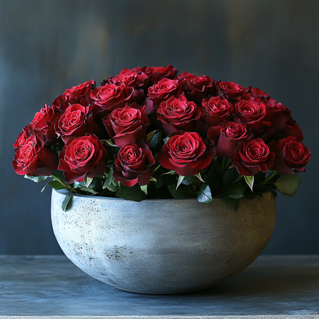 A lush arrangement of vibrant red roses arranged in a stylish, textured vase, with rich green leaves enhancing the elegance of the display, set against a soft, muted background