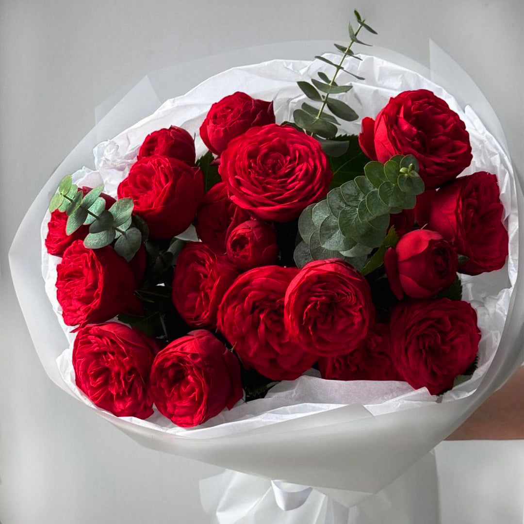 Elegant bouquet of red garden roses with eucalyptus, wrapped in white satin paper — signature floral gift by Flowers Lounge by Iness