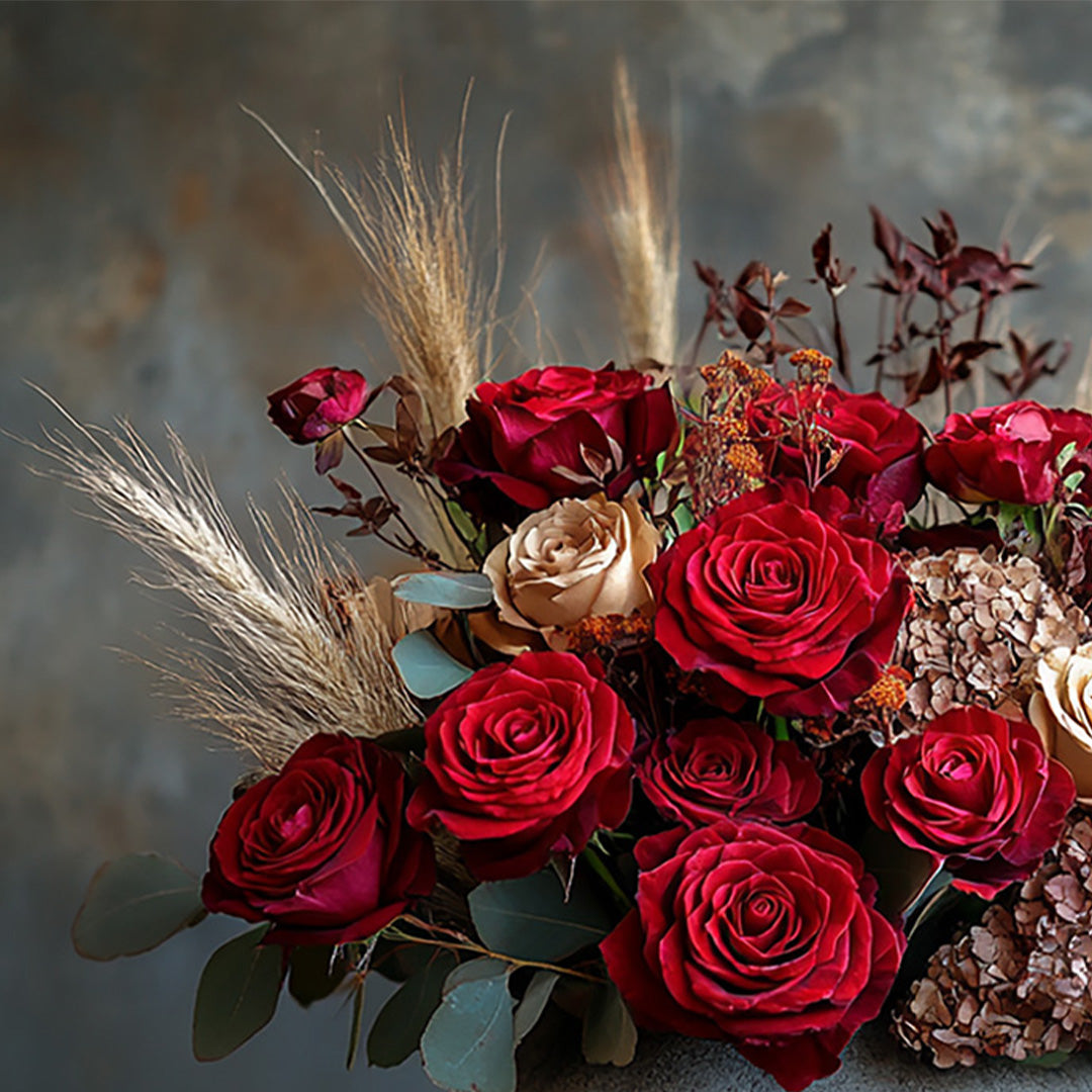 An elegant floral arrangement of deep red roses, soft cream roses, and delicate dried florals, complemented by luxurious pampas grass and rich greenery. This sophisticated bouquet exudes a warm, romantic vibe, making it ideal for special occasions or a heartfelt gift.