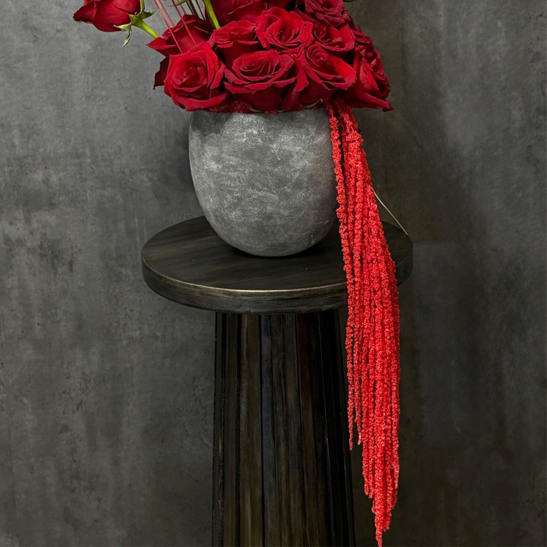 Elegant bouquet of red roses arranged in a modern grey vase, complemented by a striking long red tassel. A luxurious and dramatic floral centerpiece, perfect for romantic occasions, anniversaries, or to make a lasting impression.