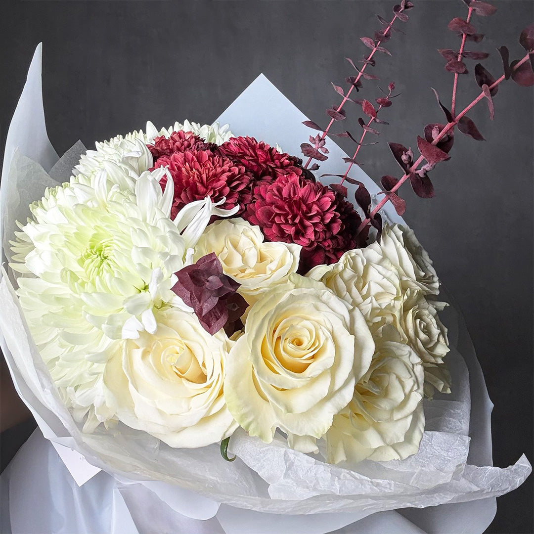 White rose and burgundy chrysanthemum bouquet wrapped in white paper with deep-toned foliage – Blushed Ivory