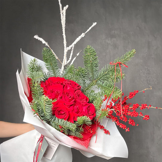 Christmas bouquet with red roses and pine branches in white and red wrapping – Holiday Flame by Flowers Lounge